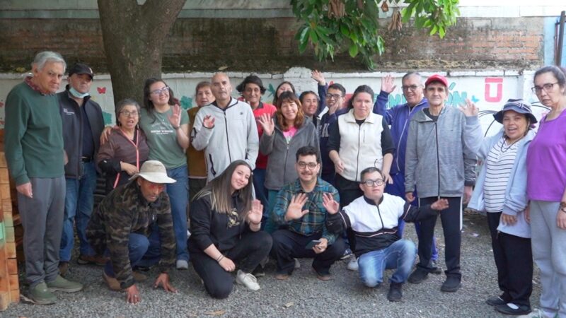 Fotografía grupal de estudiantes de la Universidad de Talca junto a personas del Servicio Diurno de la Fundación Hogar de Cristo en Linares, todos posando sonrientes.