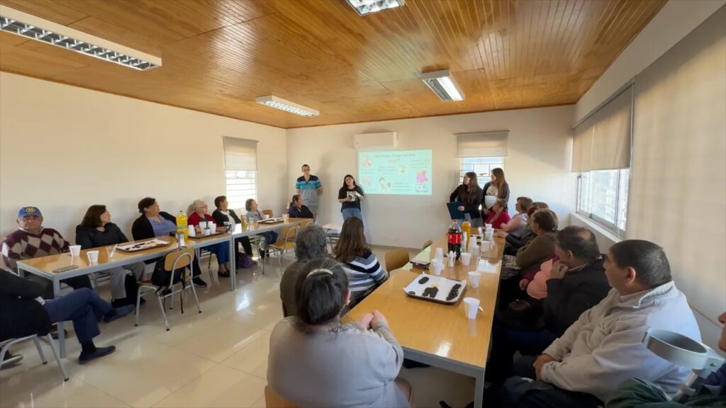 Grupo de personas sentadas en una sala prestando atención a una presentación o charla.