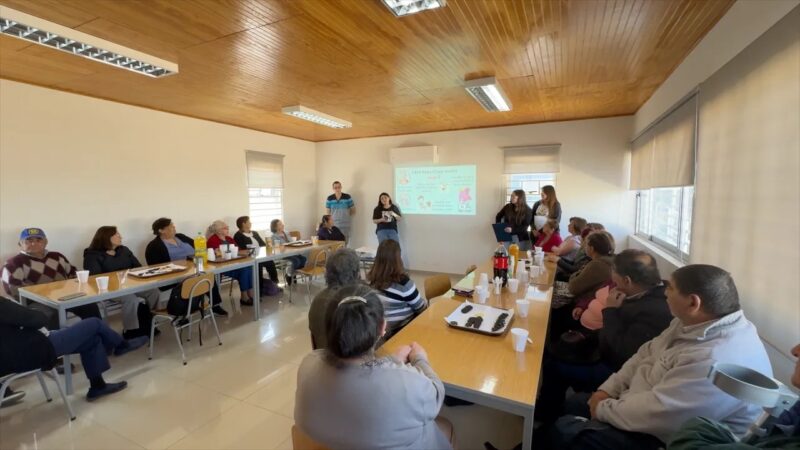 Grupo de personas sentadas en una sala prestando atención a una presentación o charla.